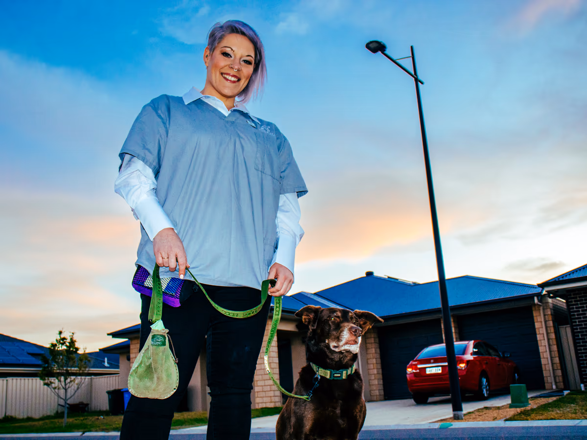 Dr Chantelle McGowan walking a dog on lead through a quiet suburban street
